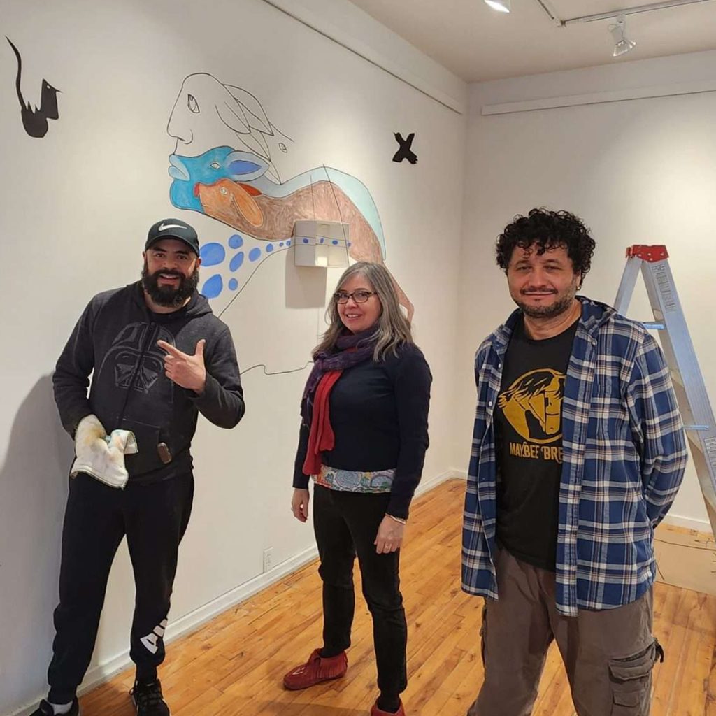 Three artists standing in front of their artwork in progress on the walls of the ARTSPLACE Main Gallery.