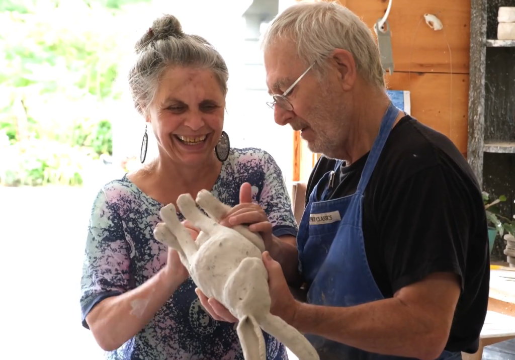 In one of their pottery studios, Deb Kuzyk manipulates a ceramic hare while Ray Mackie holds it up.